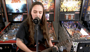Sincere Engineer performing acoustic in front of pinball machines